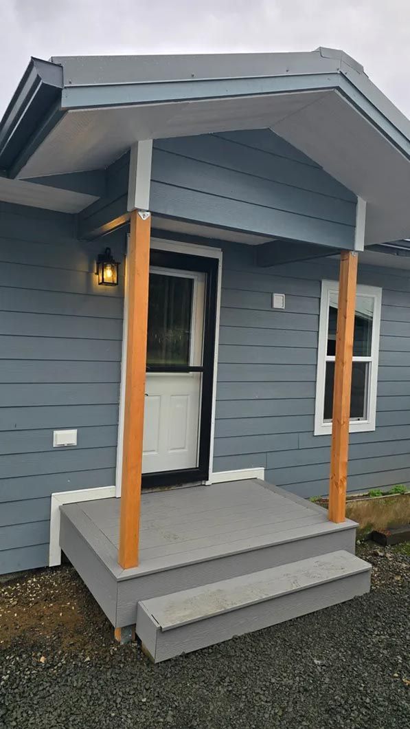 A blue house with a porch and stairs in front of it.