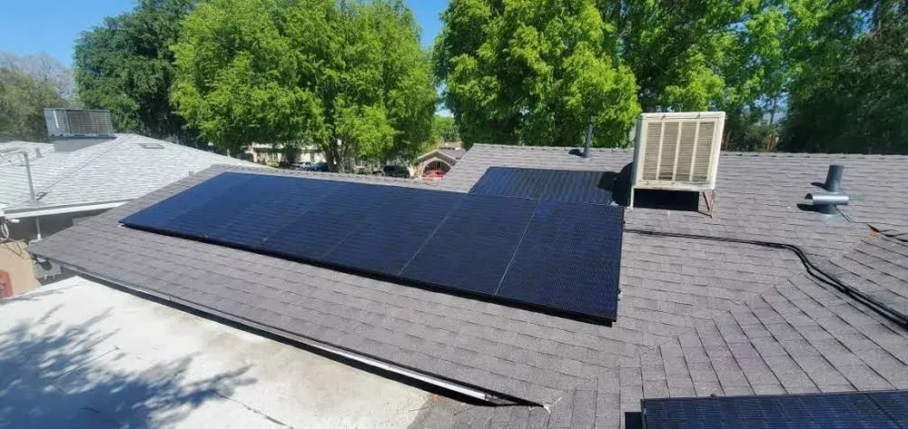 There are many solar panels on the roof of a house.