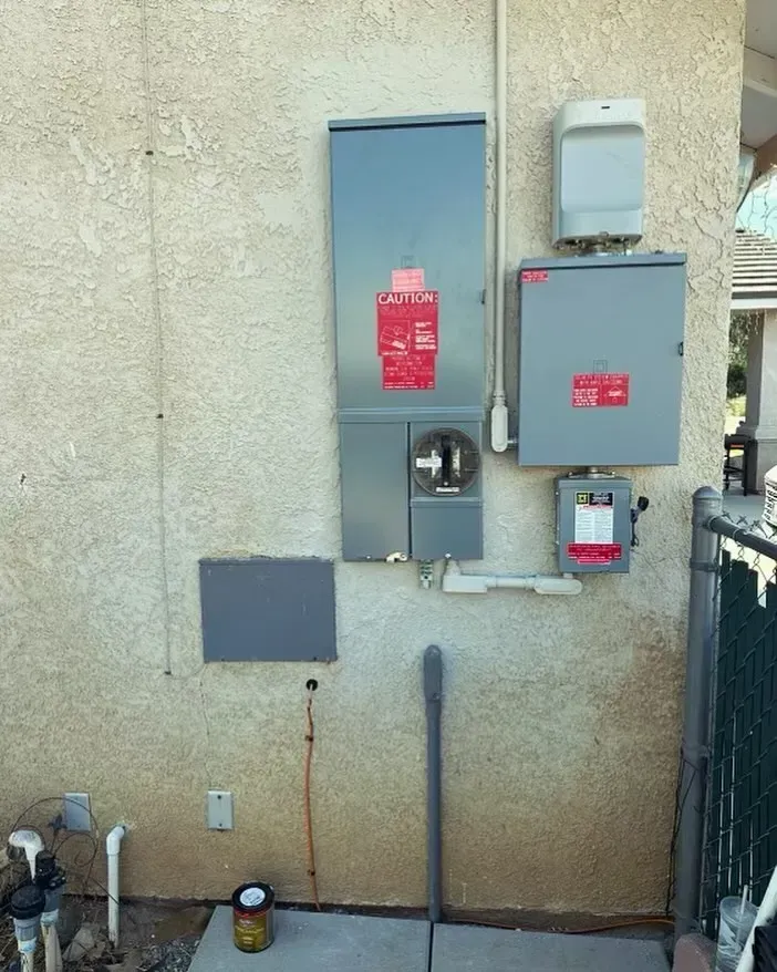 An electrical box on the side of a building with a red sticker on it