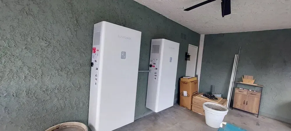 A garage with three white boxes on the wall and a ceiling fan.
