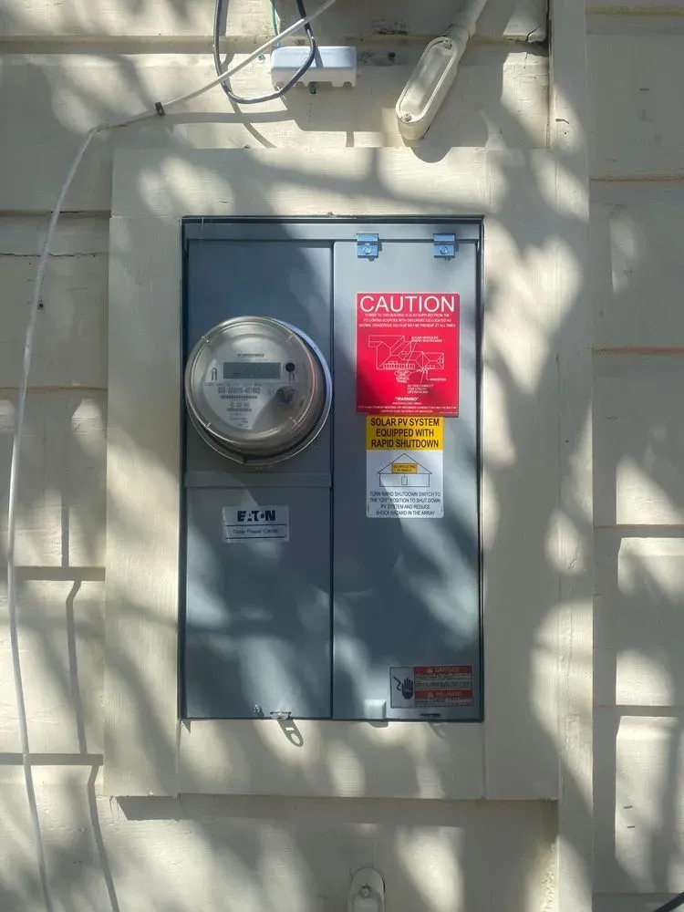 A caution sign is on a wall next to a meter