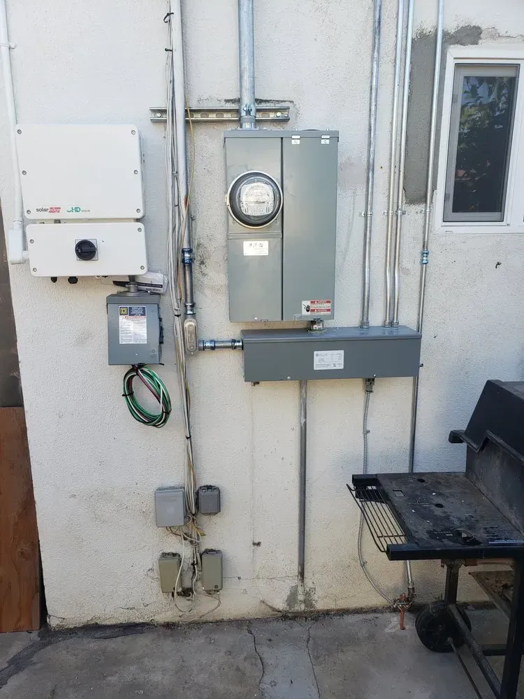 A wall with a electrical box and a meter on it.