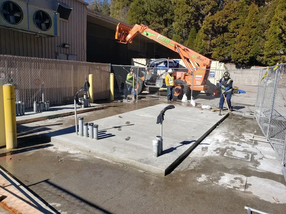 A group of construction workers are working on a concrete platform in front of a building.