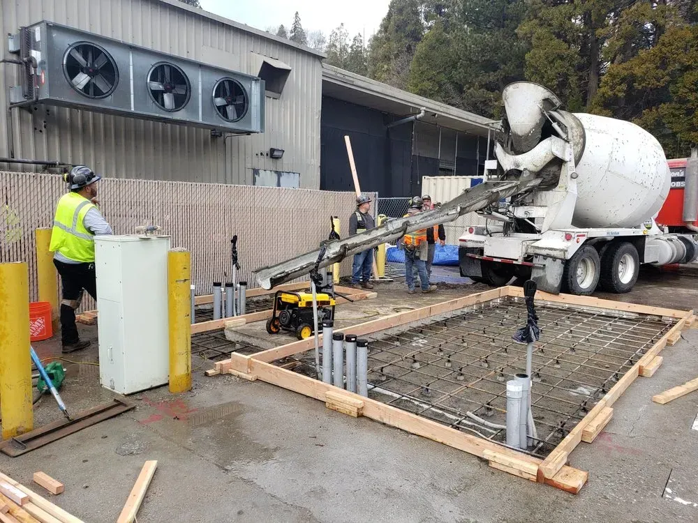 A concrete truck is pouring concrete into a concrete slab.