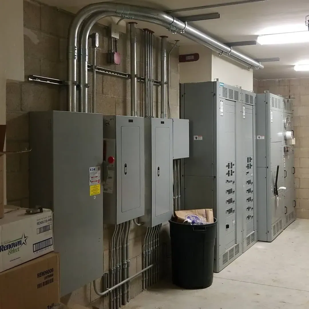 A room with lots of electrical boxes and a trash can