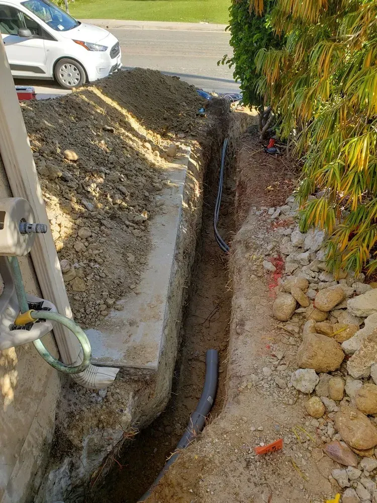 A hose is being installed in a trench next to a house.