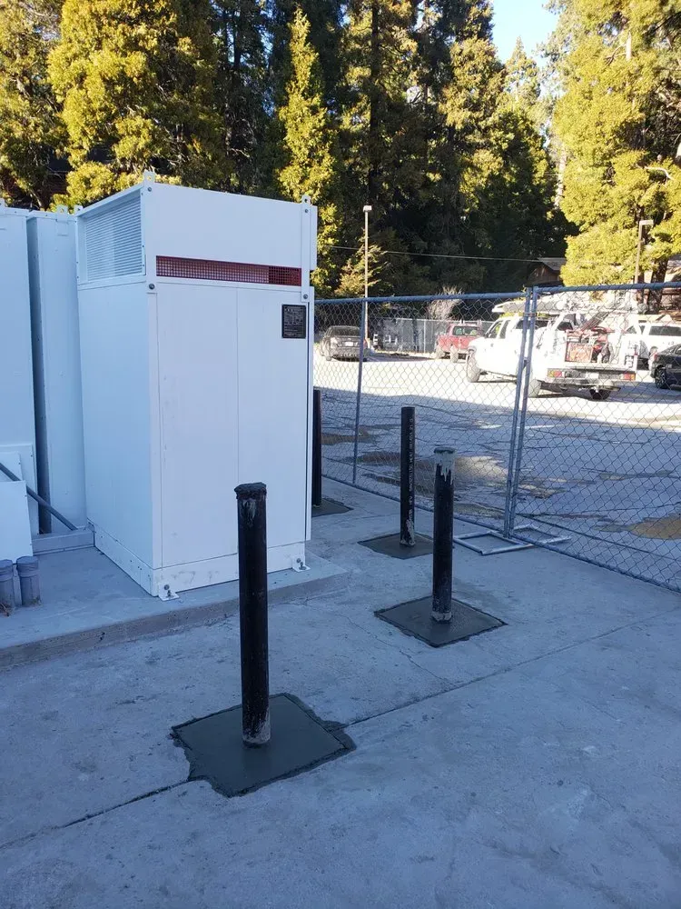 A white building is sitting in a parking lot next to a fence.