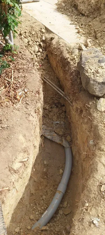A hose is laying in the dirt in a trench.