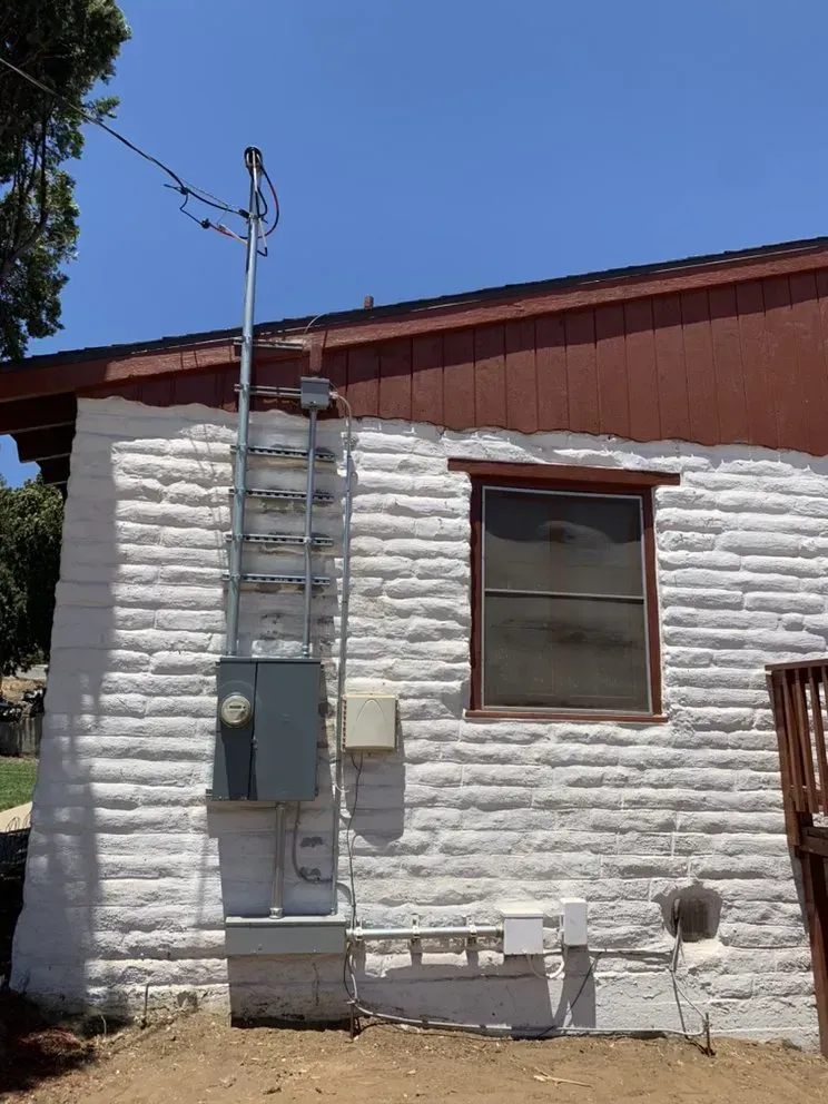 A white brick building with a window and a ladder on the side