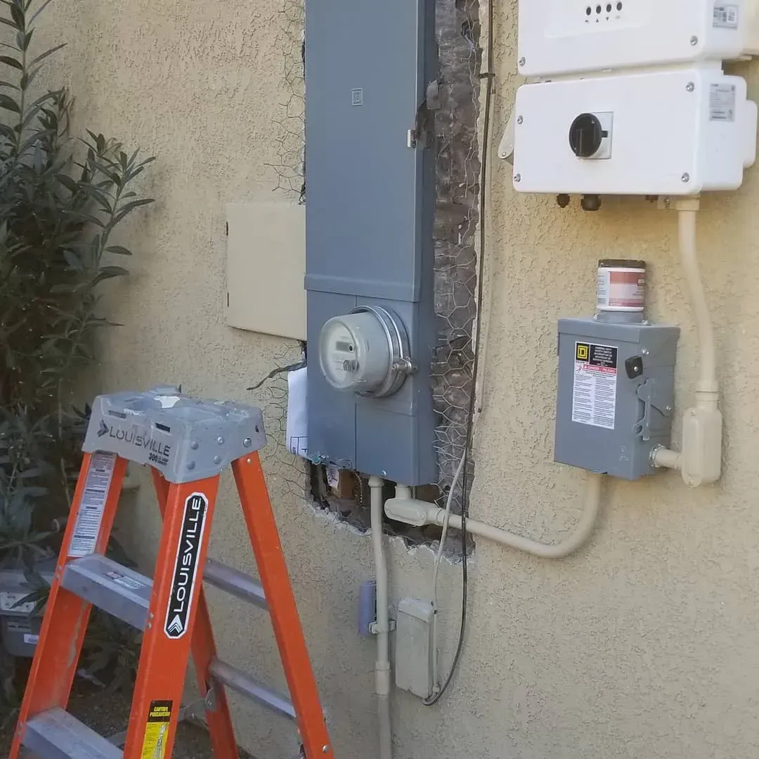 An orange ladder is sitting next to an electrical box on the side of a building
