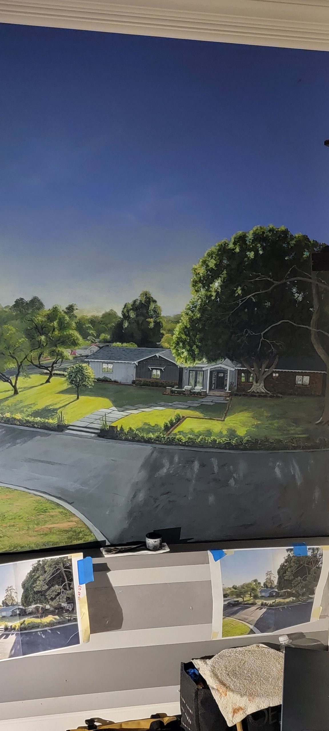 A painting of a river surrounded by trees and houses on a wall.