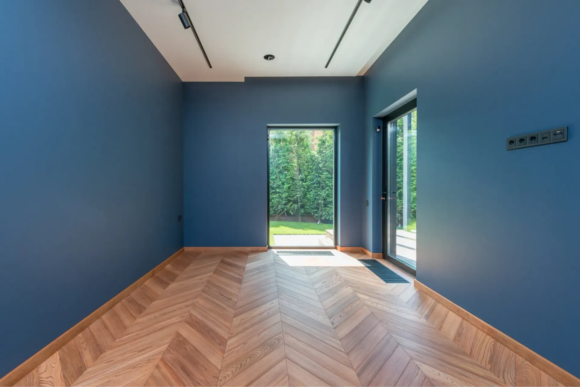 An empty room with blue walls and a wooden floor.