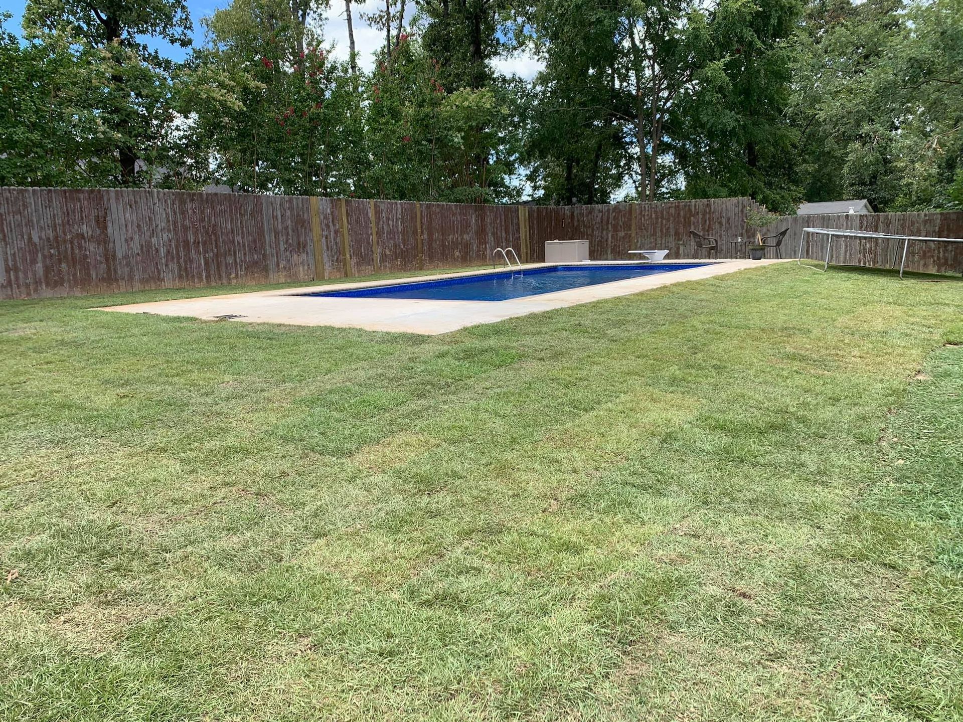 There is a large swimming pool in the middle of a lush green field.