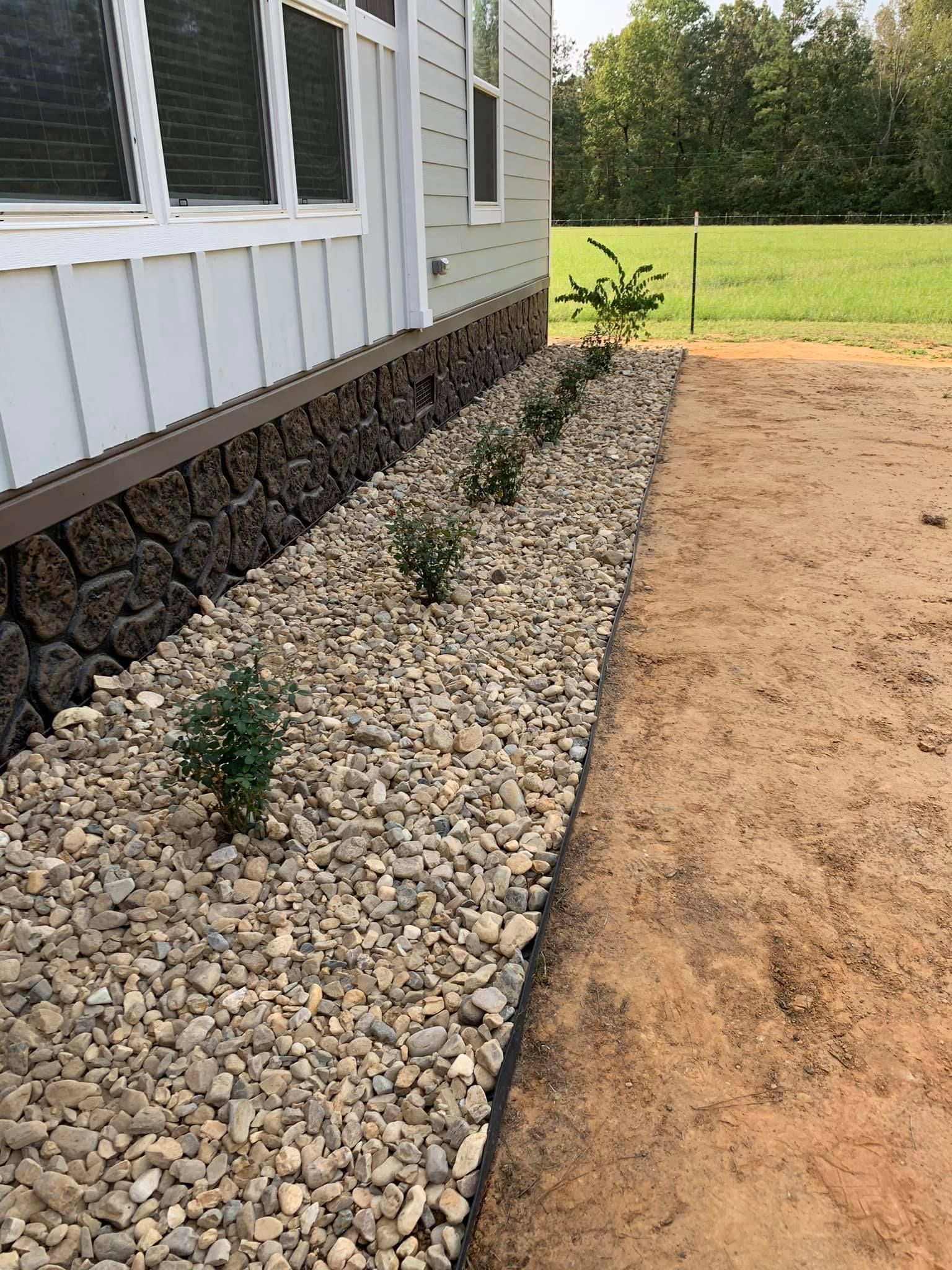 A yard with rocks and plants in front of a house.