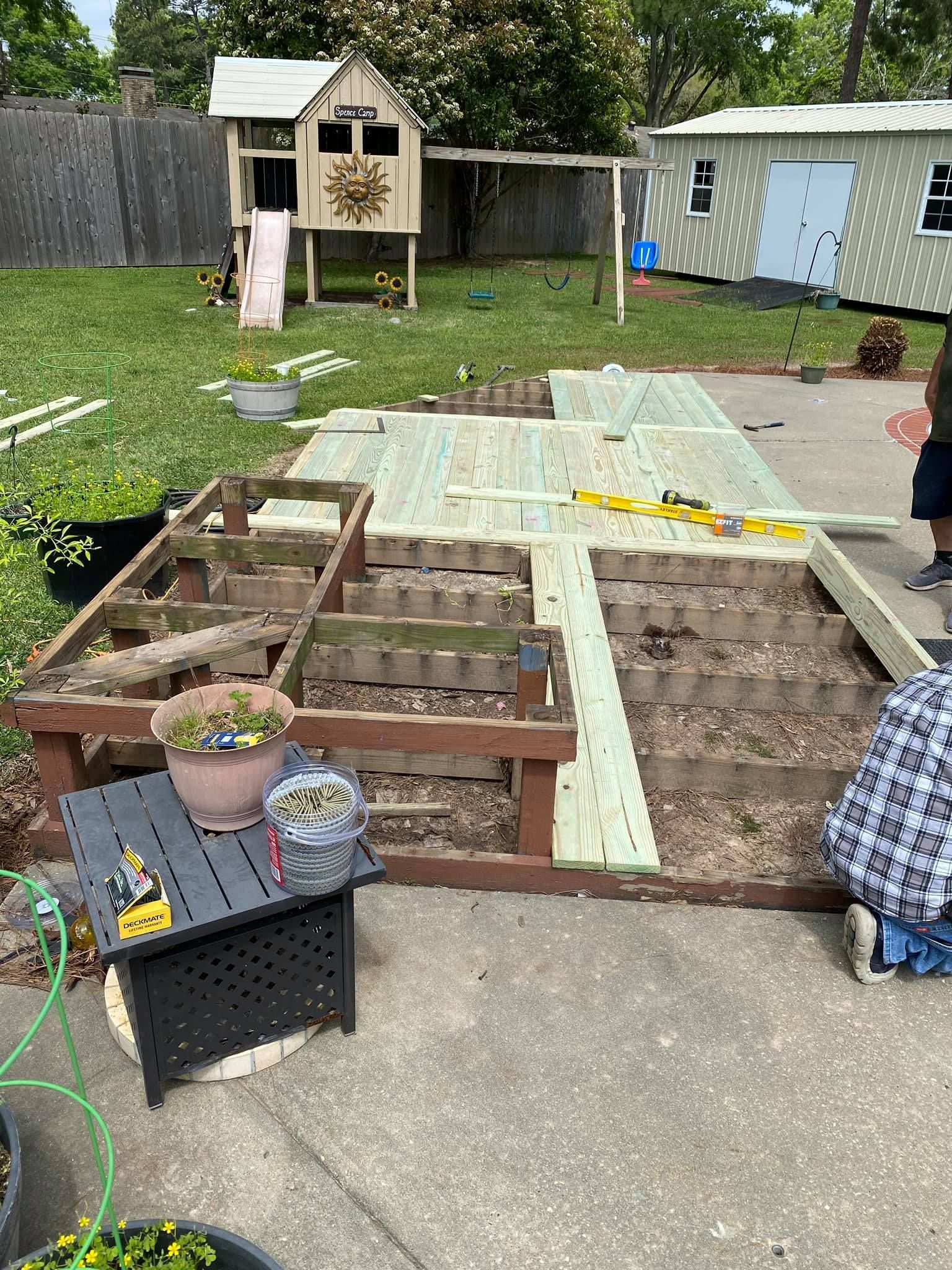 A wooden deck is being built in a backyard.