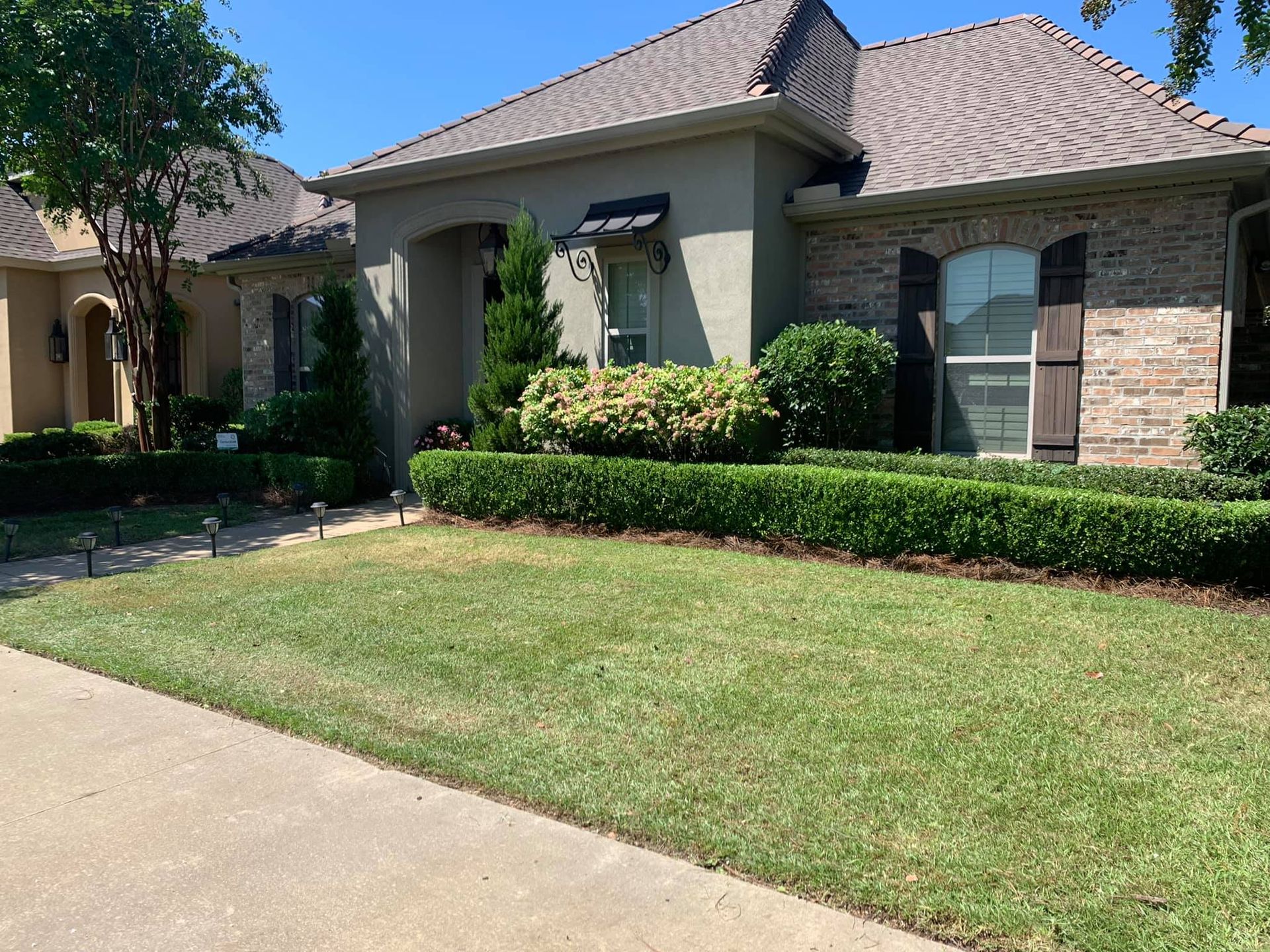 A brick house with a lush green lawn in front of it