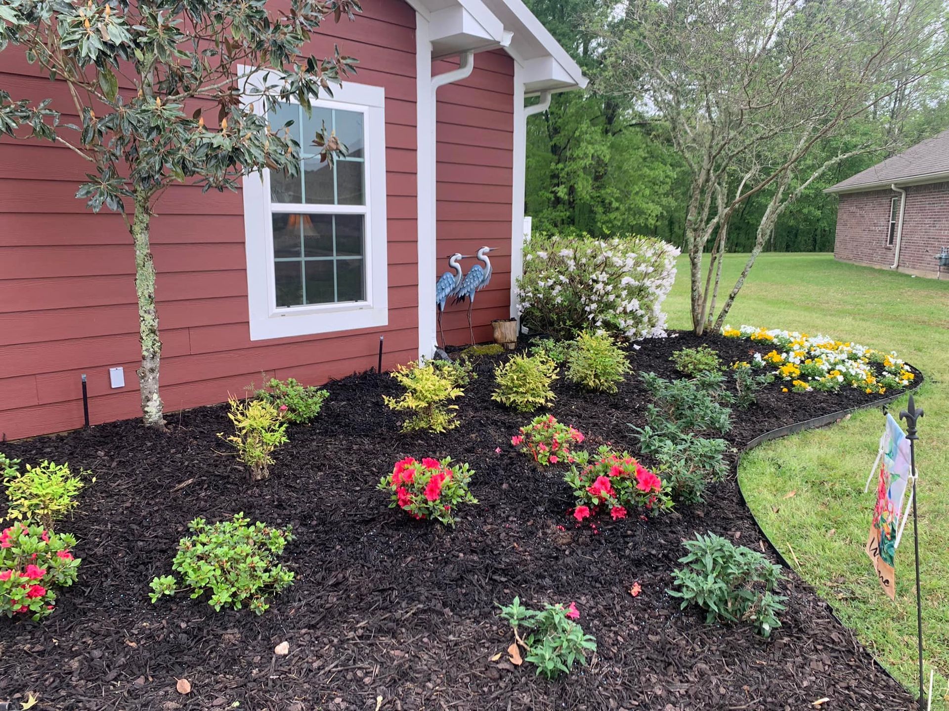 A red house with a garden in front of it.