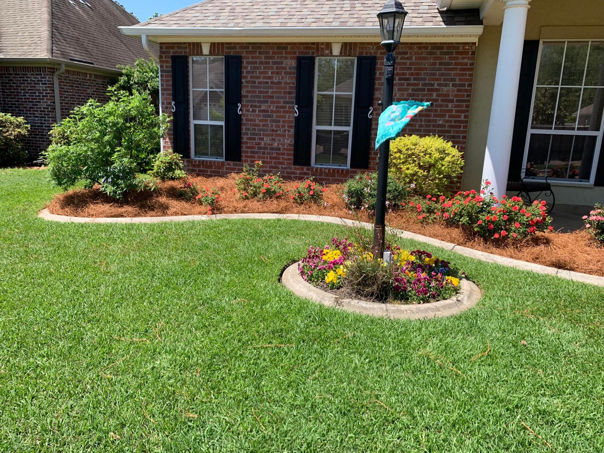 A house with a lush green lawn and flowers in front of it.