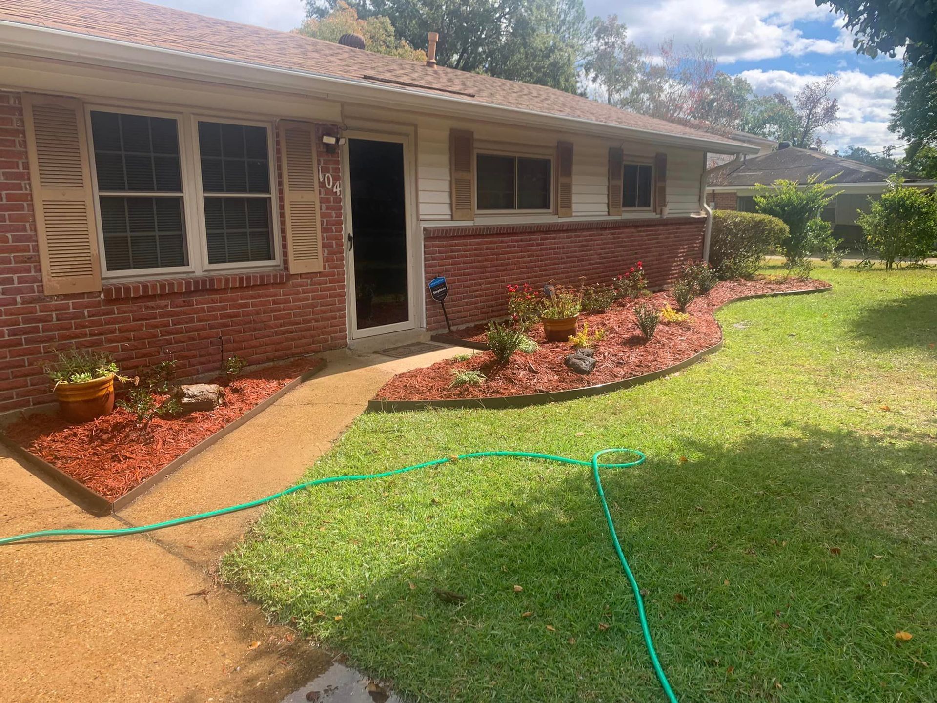 A brick house with a green hose in front of it.