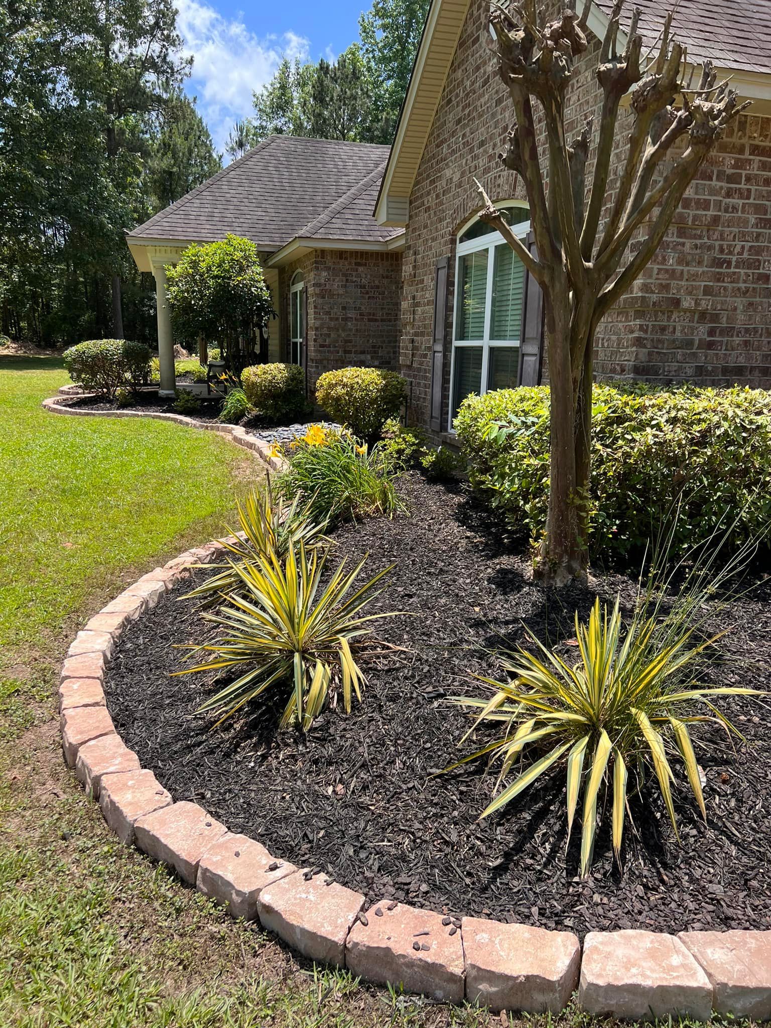 A brick house with a lush green lawn and a tree in front of it.