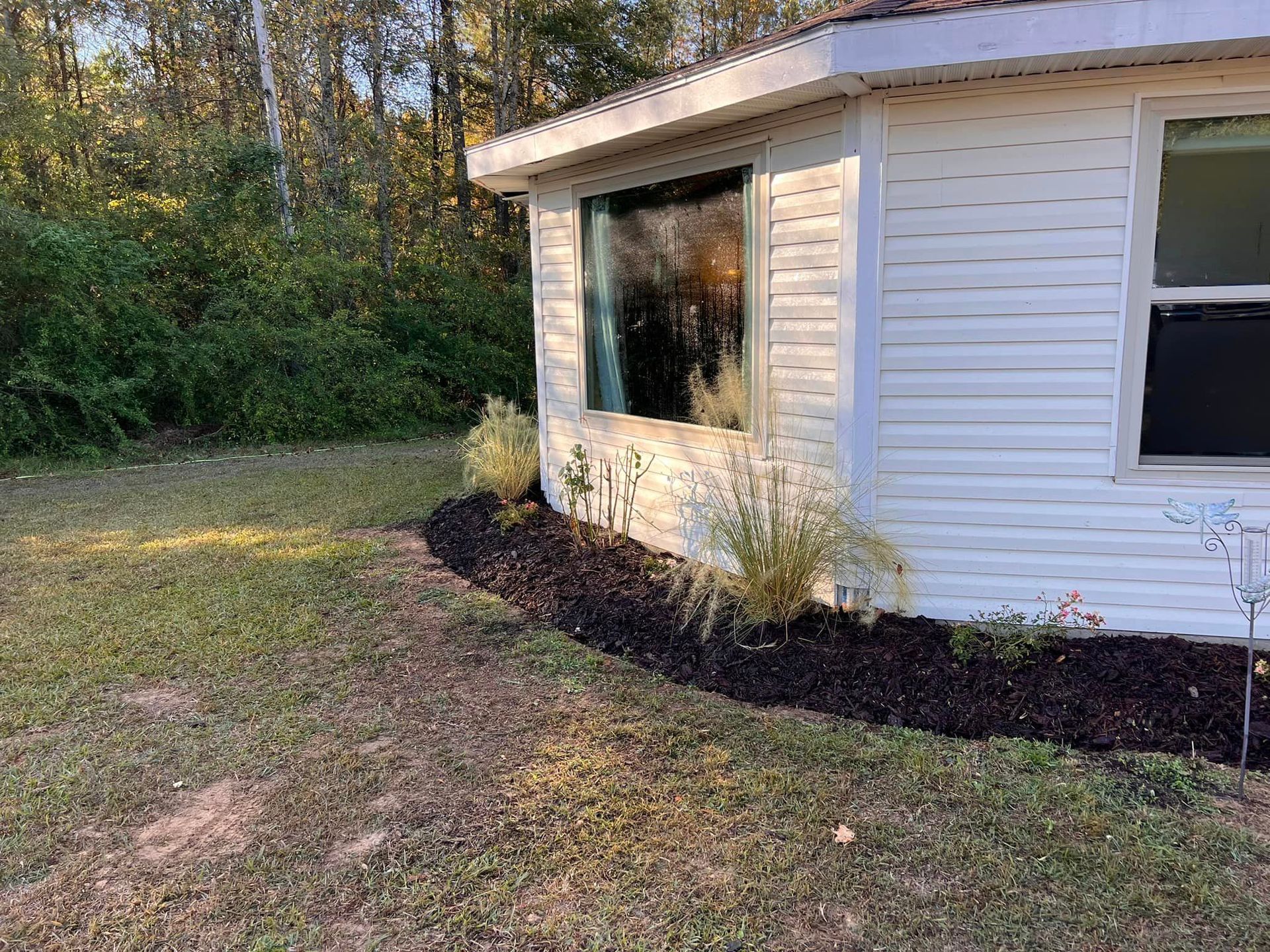 A small white house with a large window in the backyard.