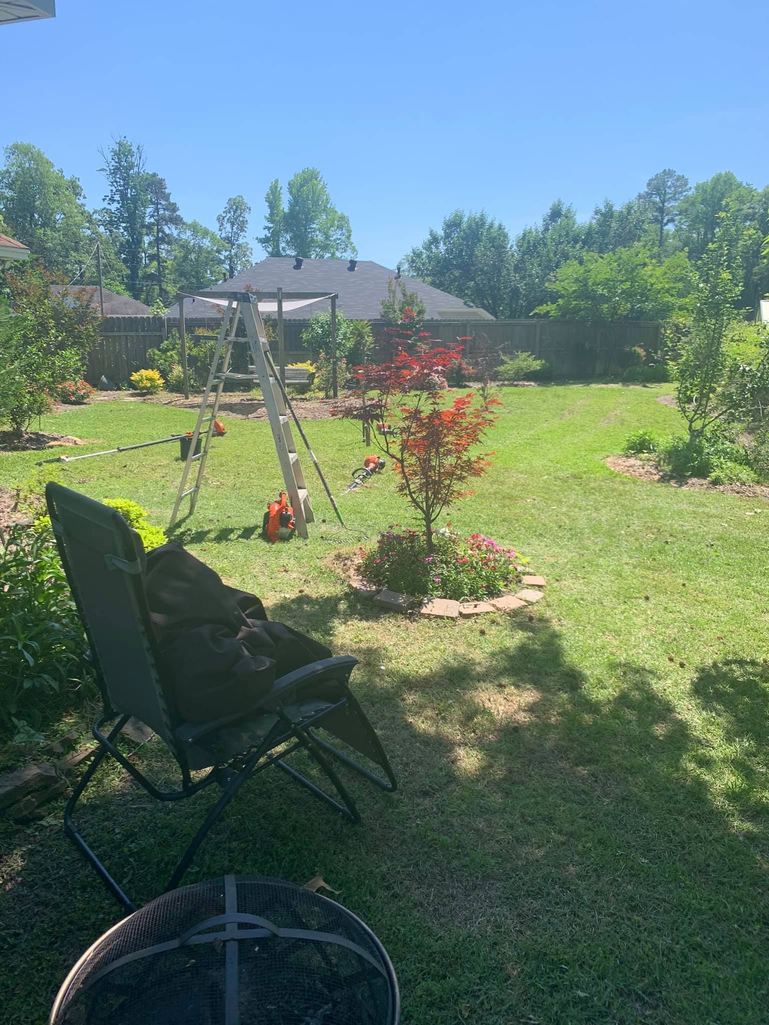 A backyard with a swing set and a chair in the grass.