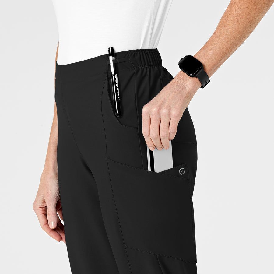 Woman wearing black scrubs, holding a card in a pocket with a pen.