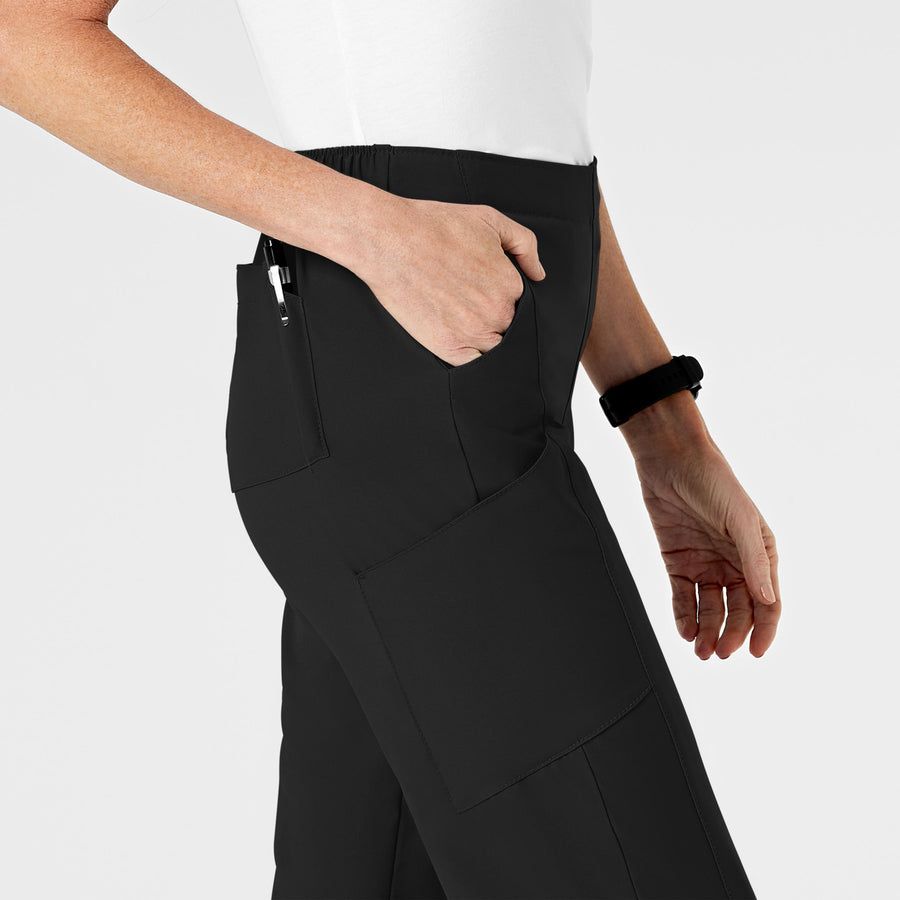 Black pants with side pockets; a hand is in one pocket, and a wrist holds a black scrunchie.