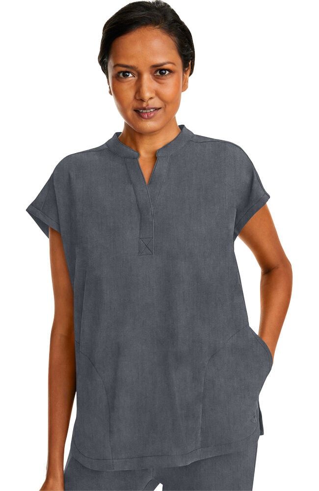Woman wearing a gray tunic top with a v-neck and short sleeves, standing outdoors.