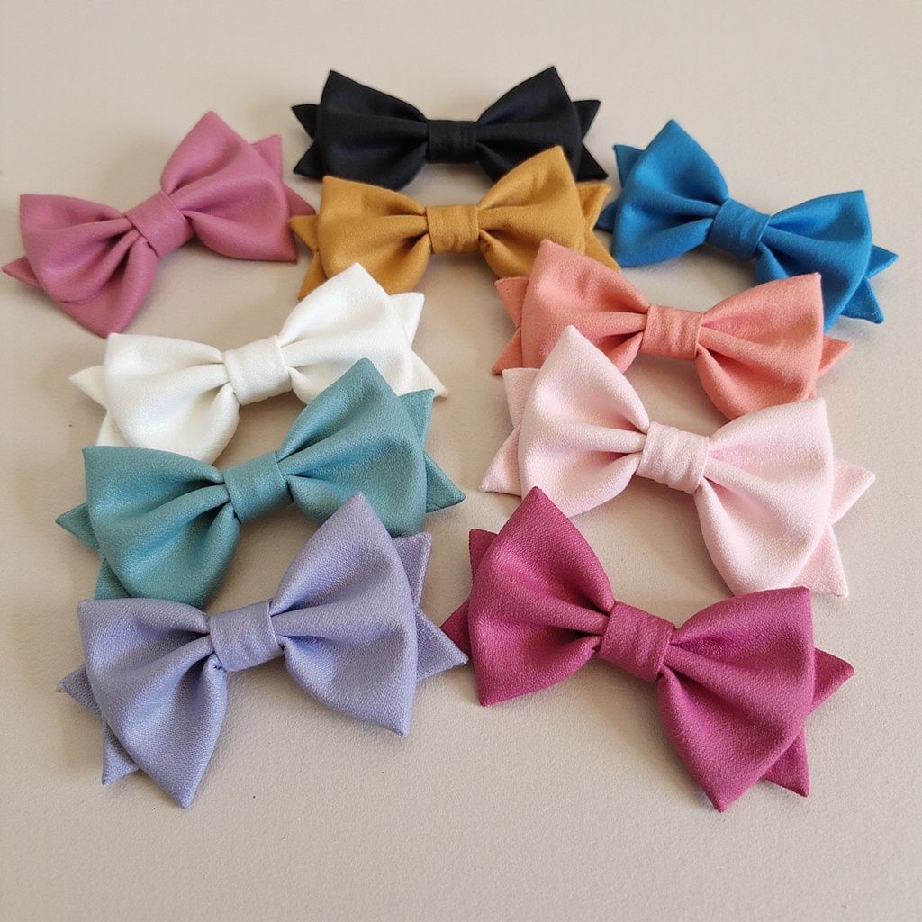 Ten colorful fabric bows in various shades arranged on a neutral surface.