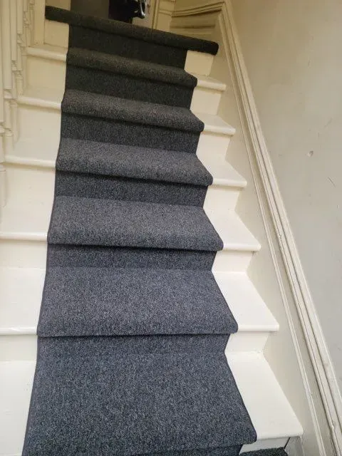 A staircase with a gray carpet on the steps and a white railing.