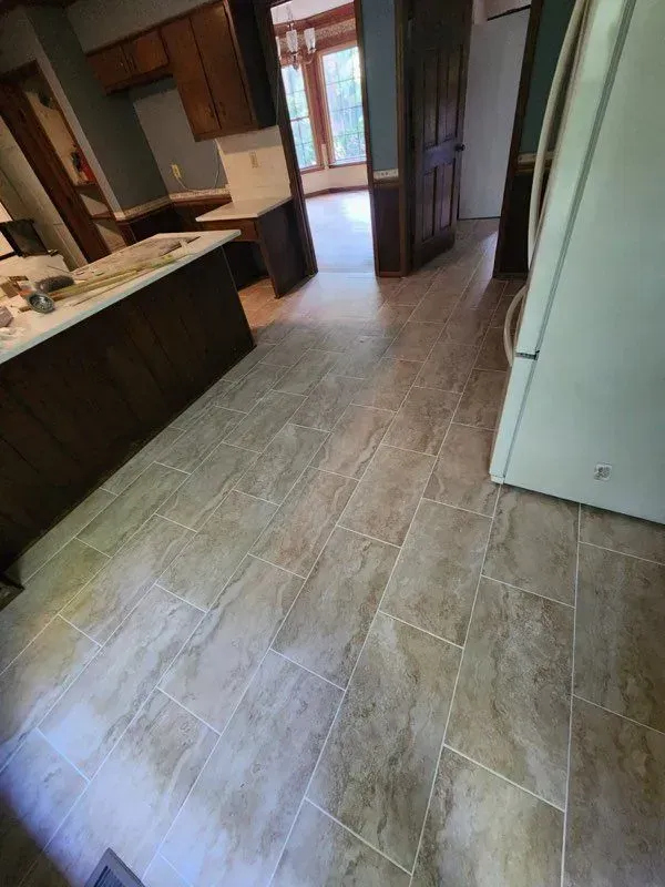 A kitchen with a tiled floor and a refrigerator.