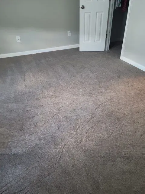 A bedroom with a carpeted floor and a door.