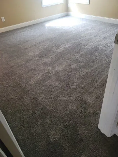 A room with a large carpeted floor and stairs leading up to it.