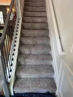 A set of stairs with a carpeted floor and a metal railing.