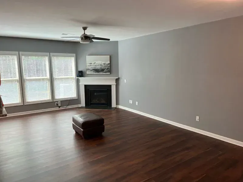 A living room with hardwood floors , a fireplace and a ceiling fan.