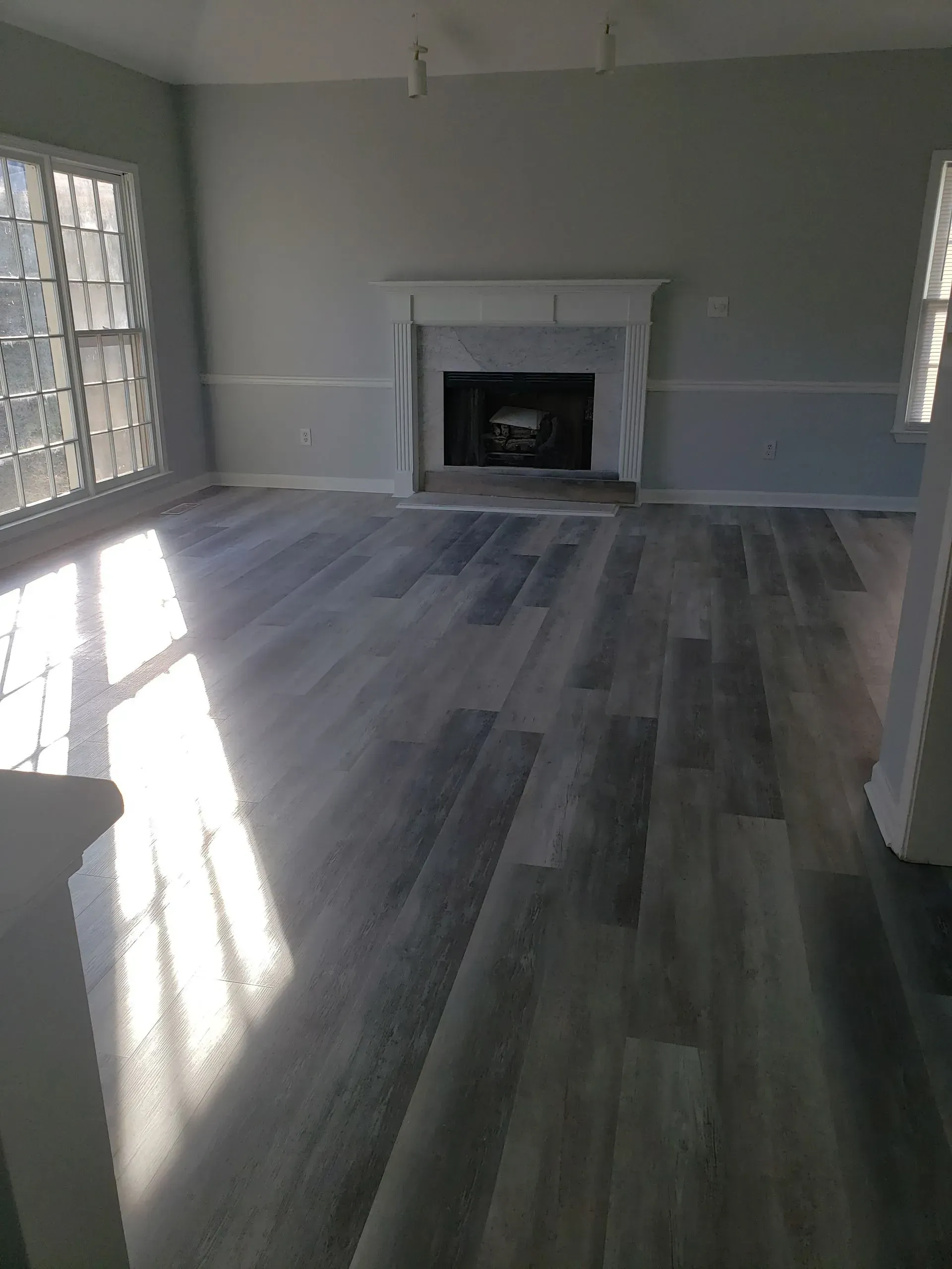 An empty living room with hardwood floors and a fireplace.