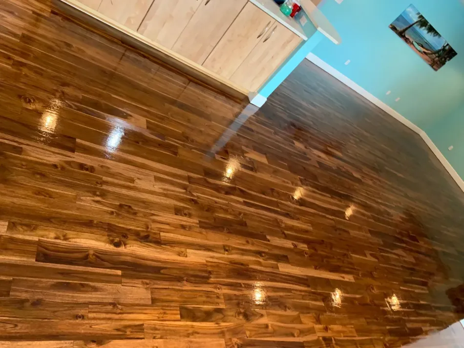 A wooden floor in a room with a kitchen in the background.