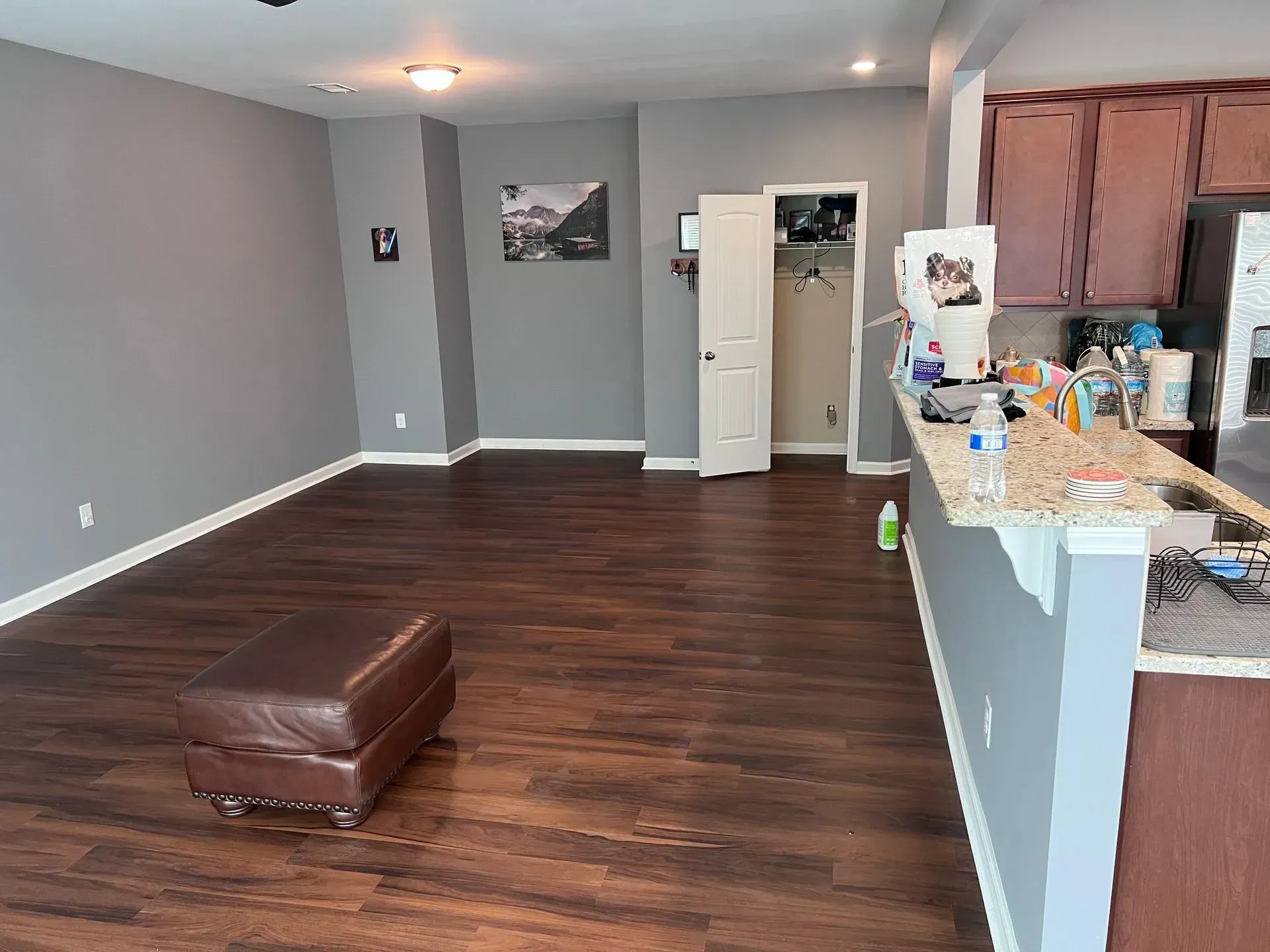 A living room with hardwood floors , a couch , and a kitchen.
