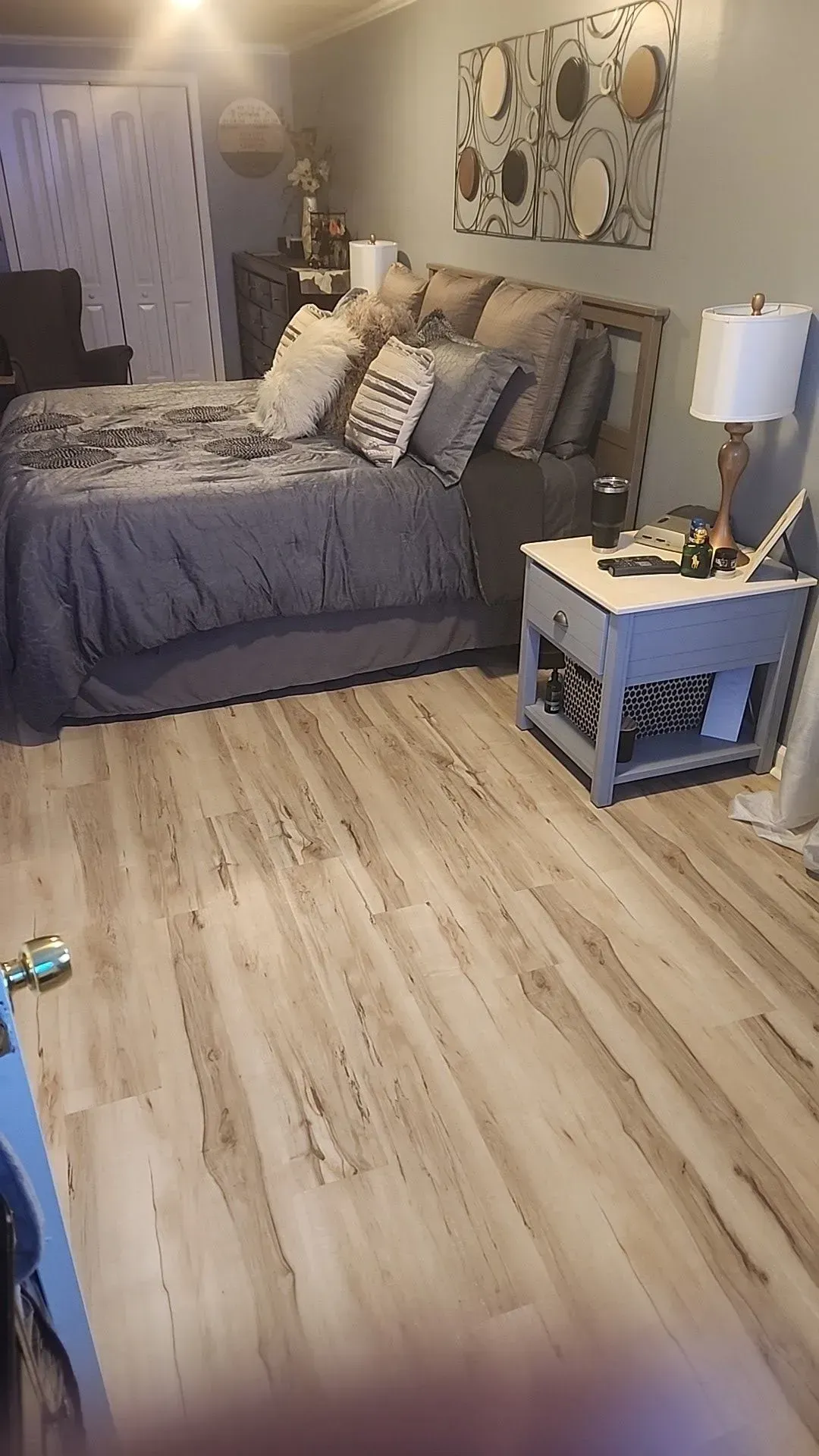 A bedroom with a bed , nightstands , lamps and a wooden floor.