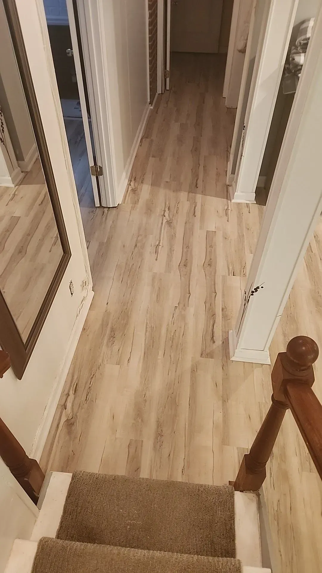 A hallway with hardwood floors and stairs leading up to the second floor.