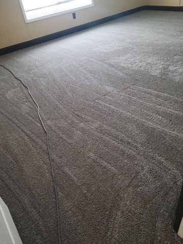 A room with a carpeted floor and a window.