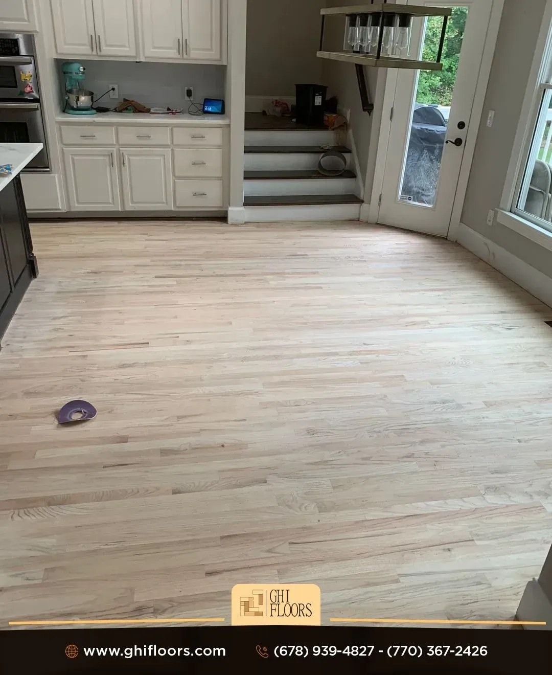 A kitchen with hardwood floors and white cabinets.