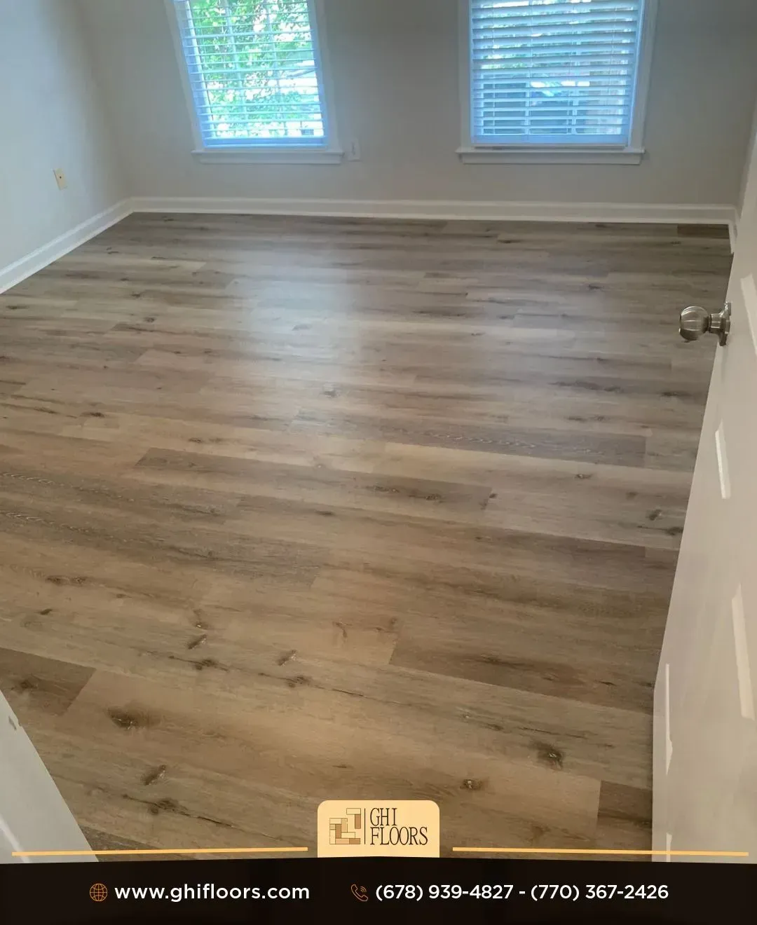 A bedroom with hardwood floors and two windows.