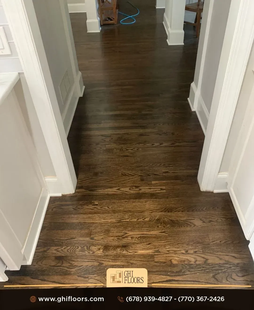 A hallway with hardwood floors and white trim in a house.