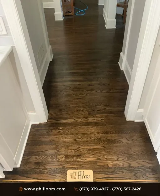 A hallway with hardwood floors and white trim in a house.