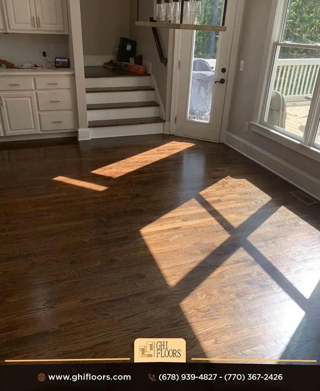 A living room with hardwood floors and white cabinets and stairs.