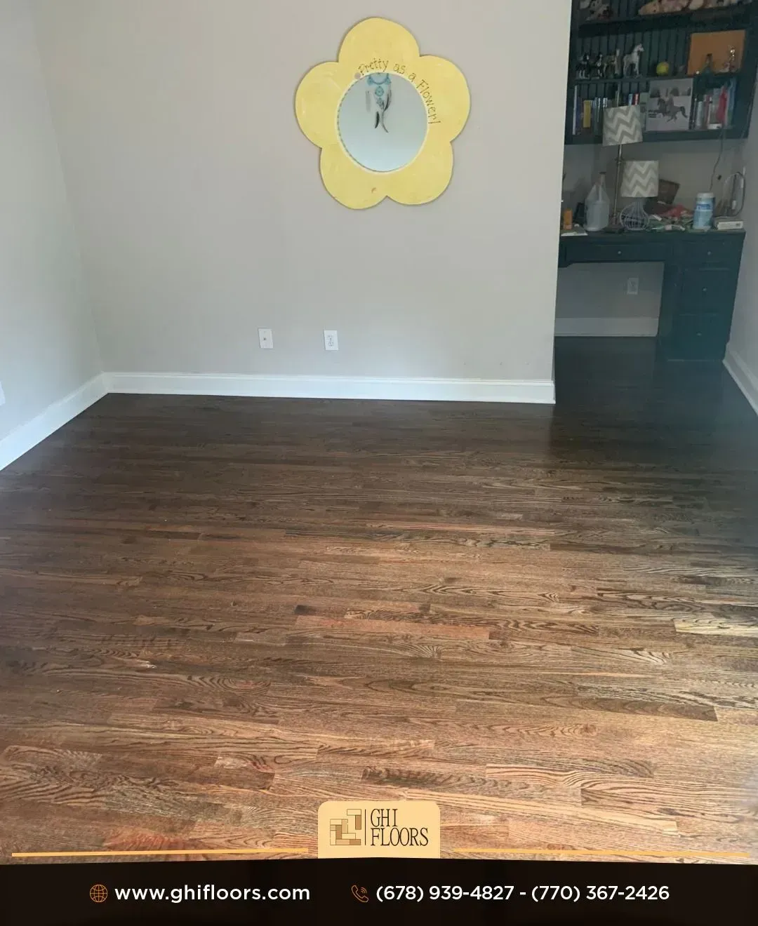 A room with a wooden floor and a yellow mirror on the wall.