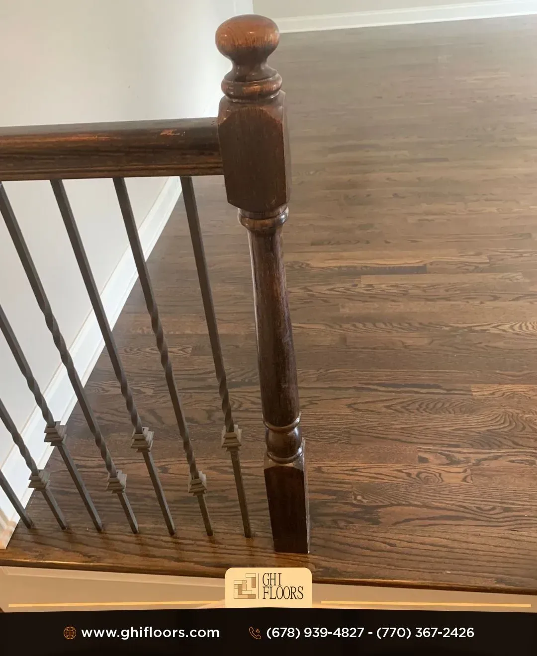 Dark wooden staircase with dark brown railing and metal balusters, with dark wood flooring.