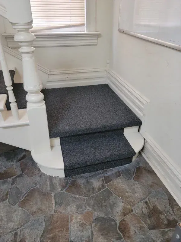 A staircase with a carpeted staircase and a stone floor.